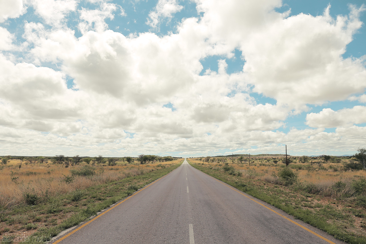 Foto von An open road stretches into the horizon under a cloud-draped sky in Otjozondjupa, Namibia.