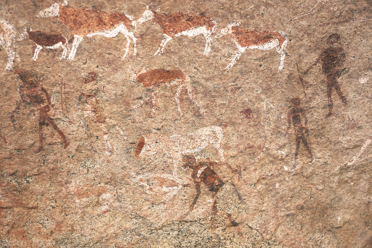Foto von Ancient rock art in Brandberg, Namibia, showcasing human and animal figures etched in stone.