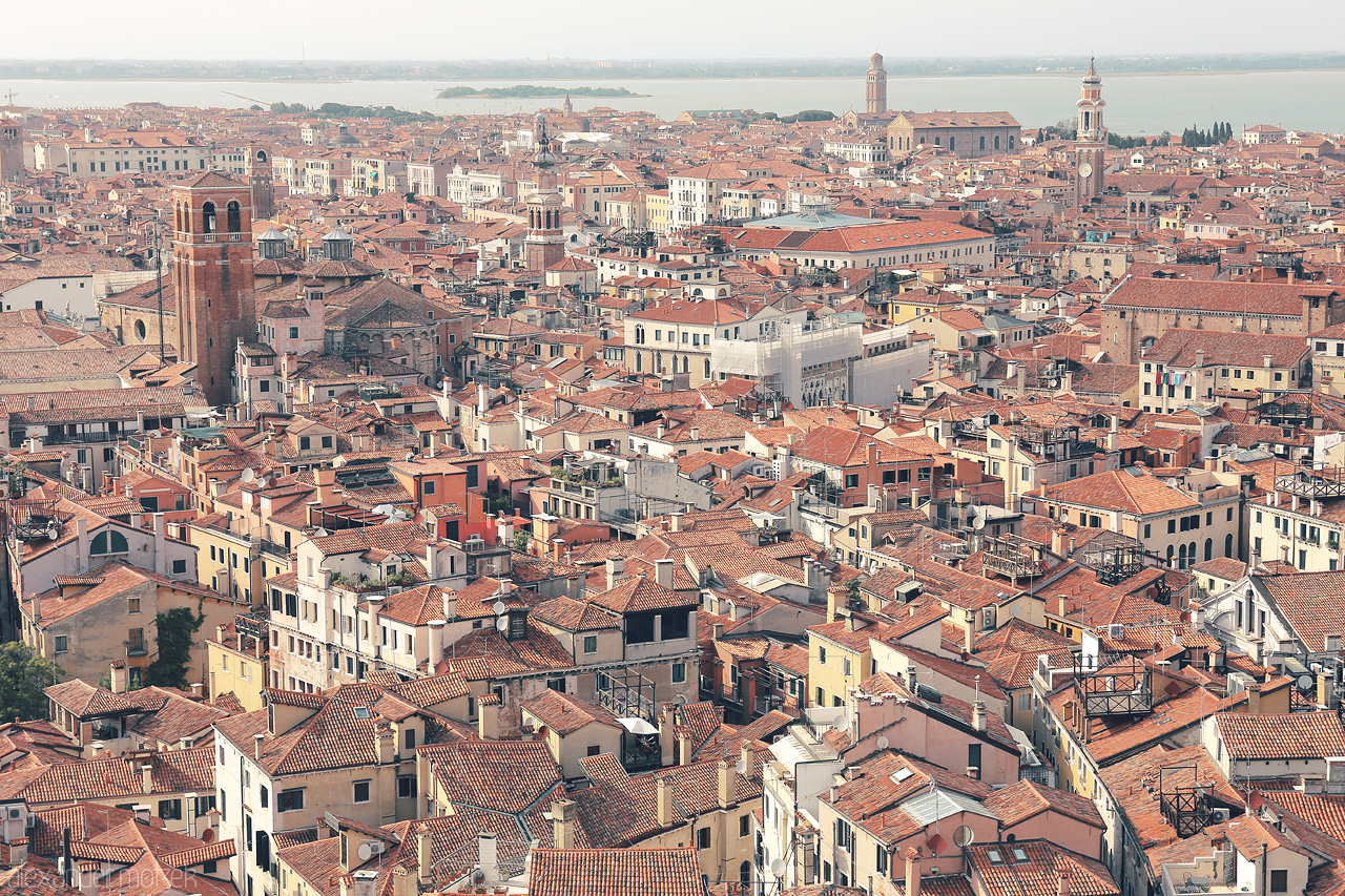 Foto von A sun-kissed expanse of Venetian rooftops, bell towers piercing the skyline, and the lagoon's shimmer in the distance.