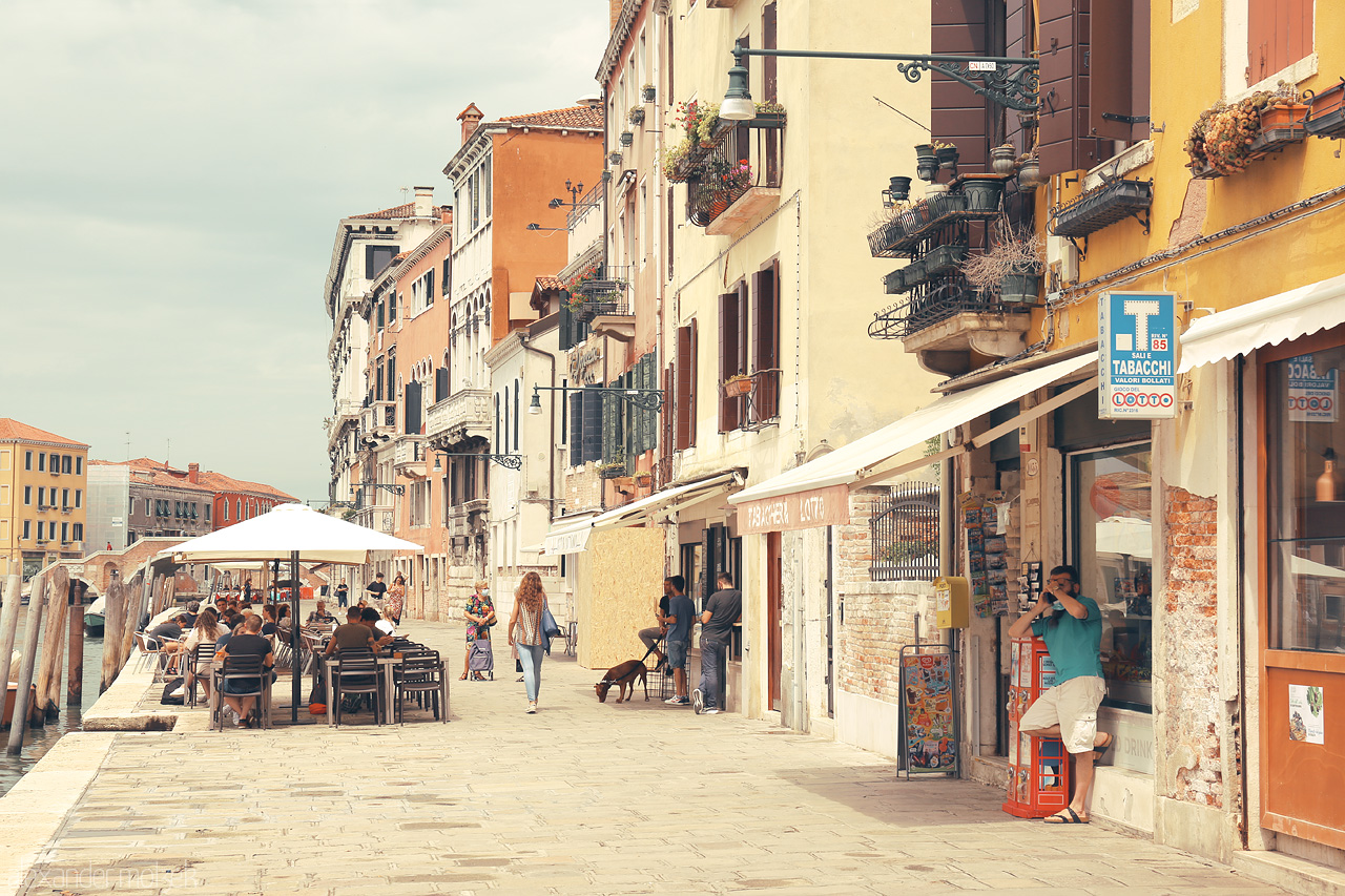 Foto von Cafes and boutiques line a Venetian street, echoing with the murmur of a lively afternoon in Venice.