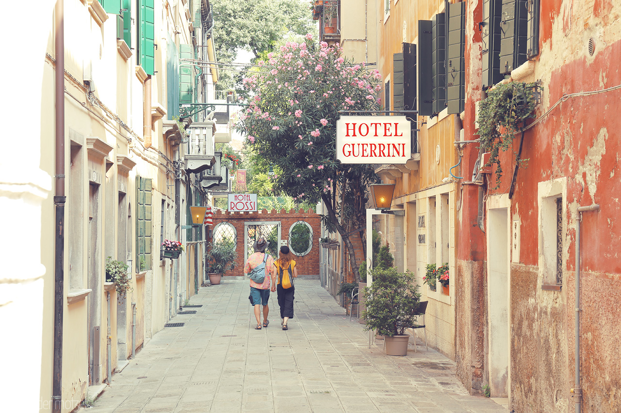 Foto von Strolling through a serene Venetian alley, flanked by historic facades and blooming flora under a soft sky.