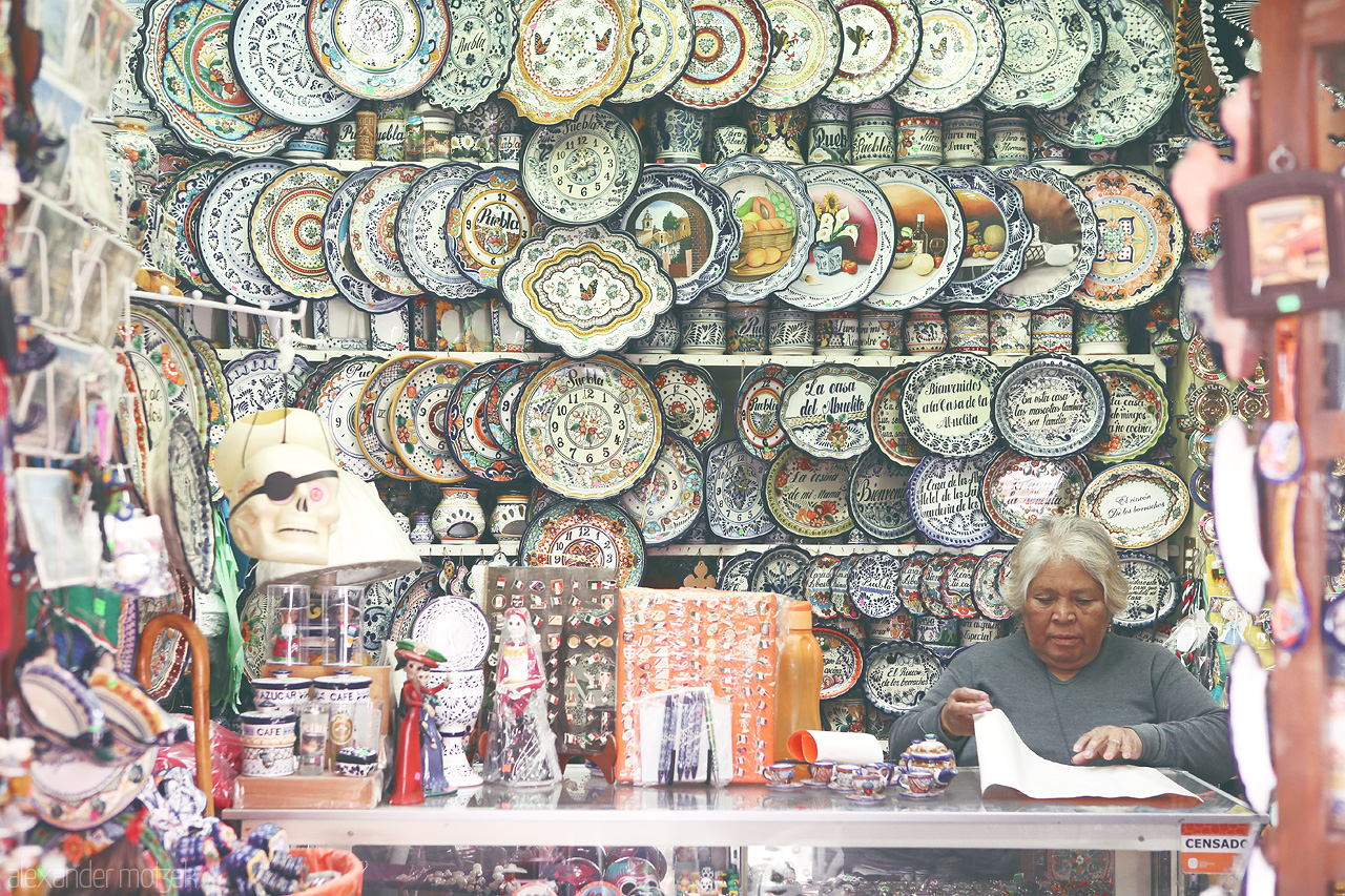 Puebla Platería Foto von A colorful display of traditional Puebla pottery with intricate designs, as a local artisan engages in her craft.