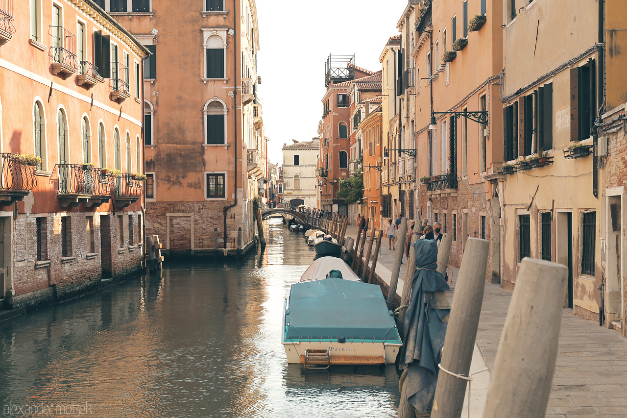 Serenissima Suggestioni Foto von A serene canal lined with historic Venetian architecture, a bridge in the distance, under the soft glow of dusk.