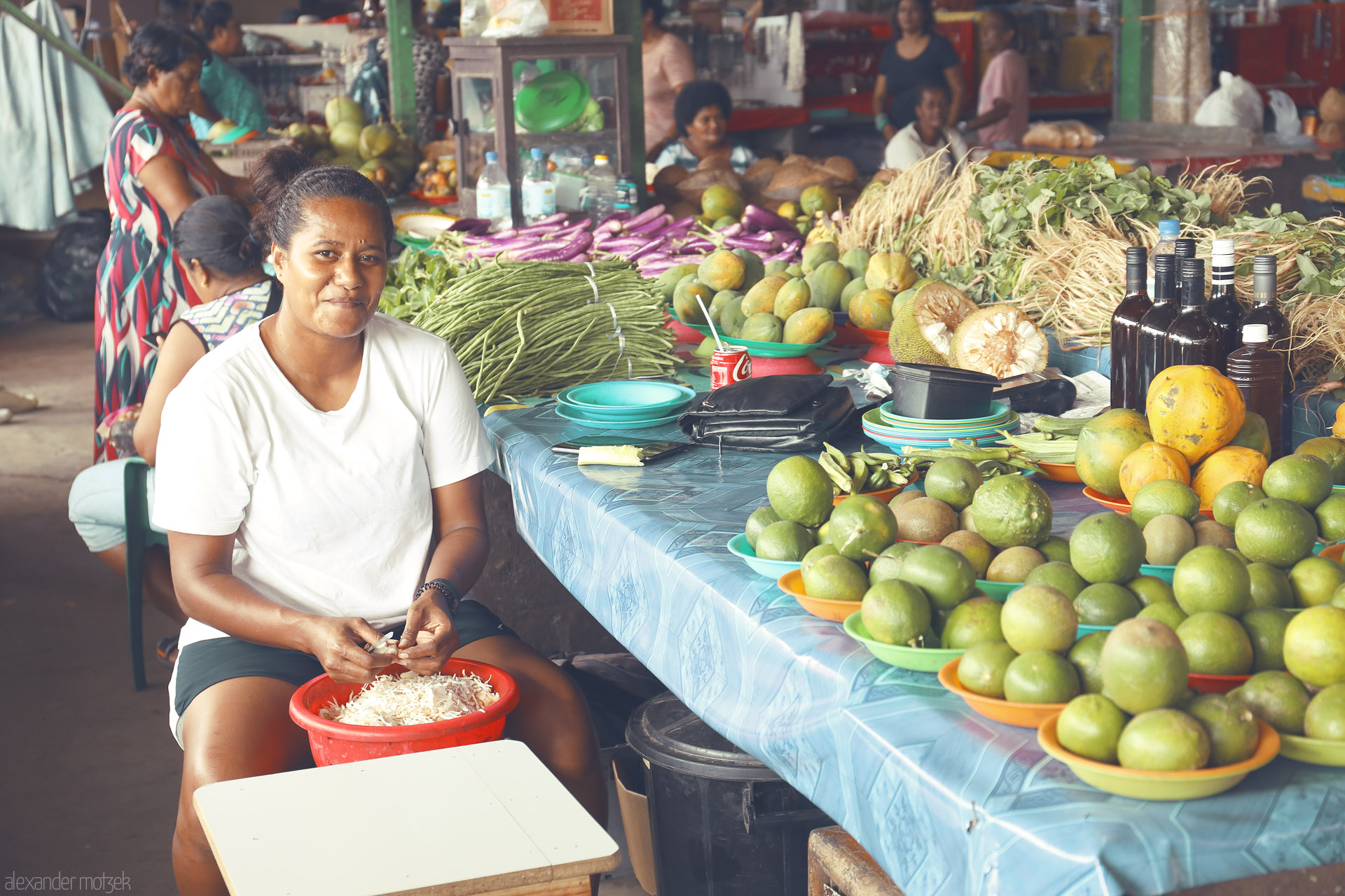 Foto von A smiling vendor amid bowls of limes, mangoes and island greens at Sigatoka Market, Fiji.