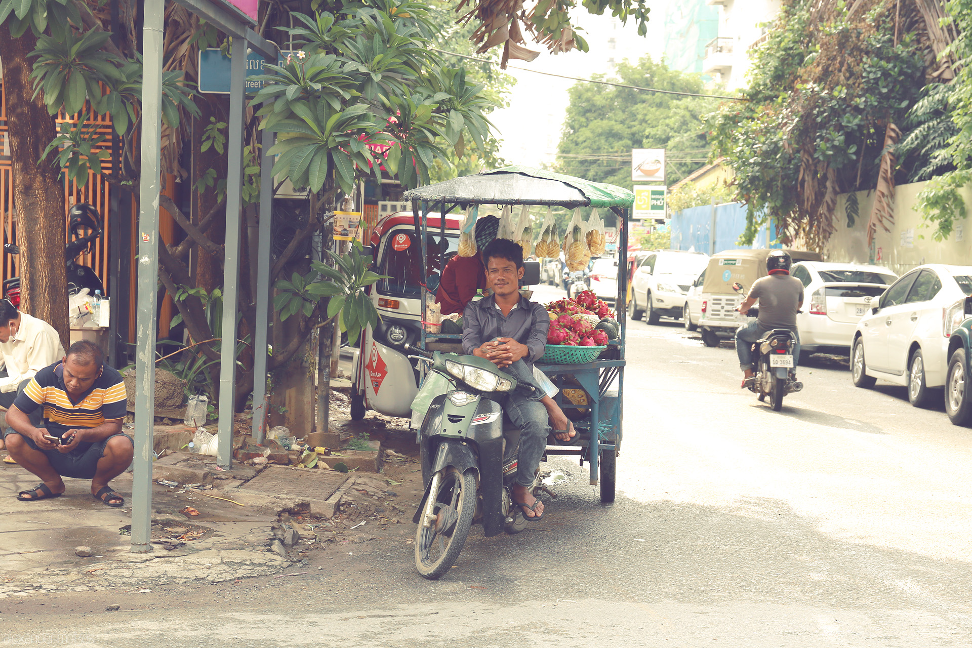 Foto von A street vendor on his moto-cart offers bright dragonfruit and snacks on a typical sunlit Phnom Penh street, Cambodia.