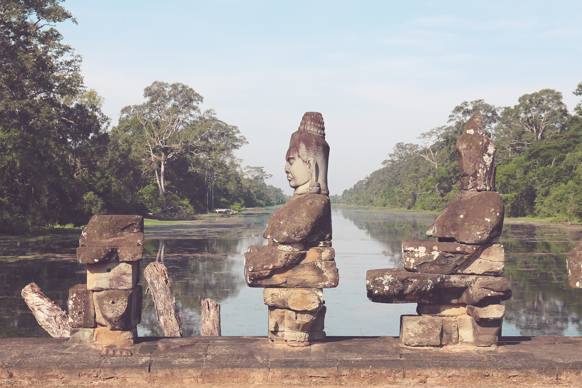 Foto von Ancient stone guardians gaze serenely over the water at Angkor Wat, Siem Reap, Cambodia, surrounded by lush jungle and tranquil reflection.
