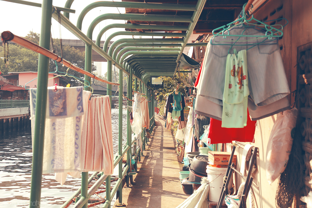 Foto von A vibrant passage by the canal in Thanon Phetchaburi, Bangkok, adorned with colorful drying clothes and local life.