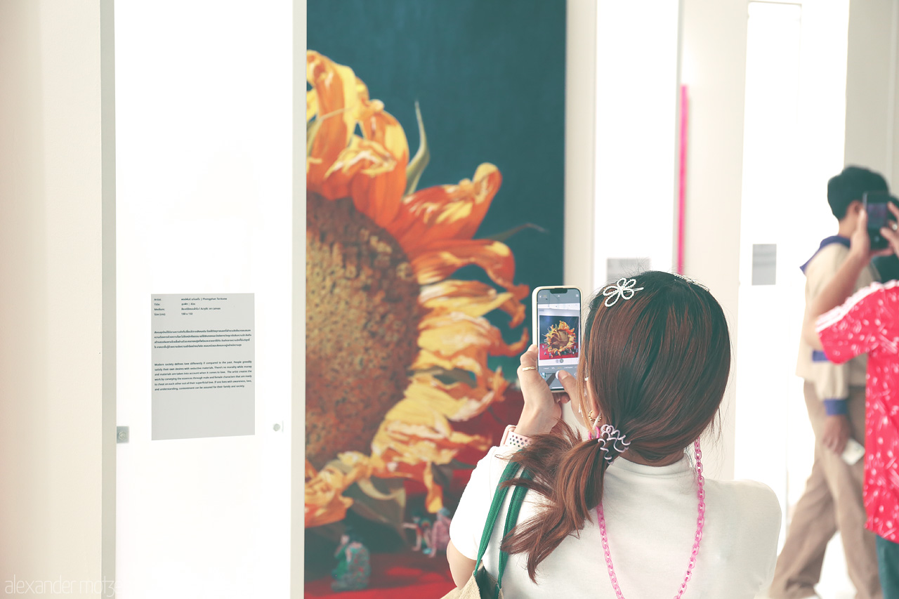 Foto von A visitor captures a vivid sunflower painting in Wang Mai, Bangkok, blending art with life.