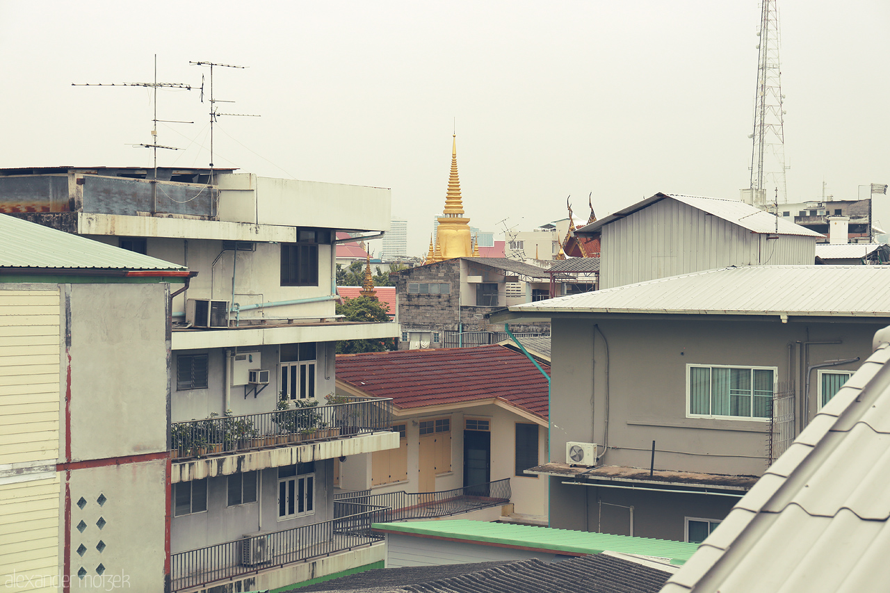 Foto von In Ban Phan Thom, Bangkok, a golden temple spire rises above the urban tapestry, blending tradition with modernity.