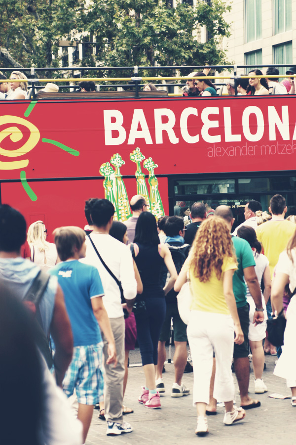 Foto von A bustling crowd moves along the vibrant streets of Barcelona, capturing the city's lively essence beneath a sunlit sky.