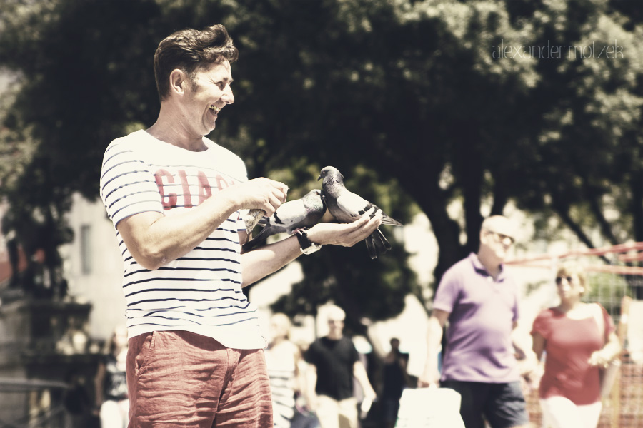 Foto von A joyful moment captures a man feeding pigeons in sunny Barcelona, surrounded by vibrant life on La Rambla.