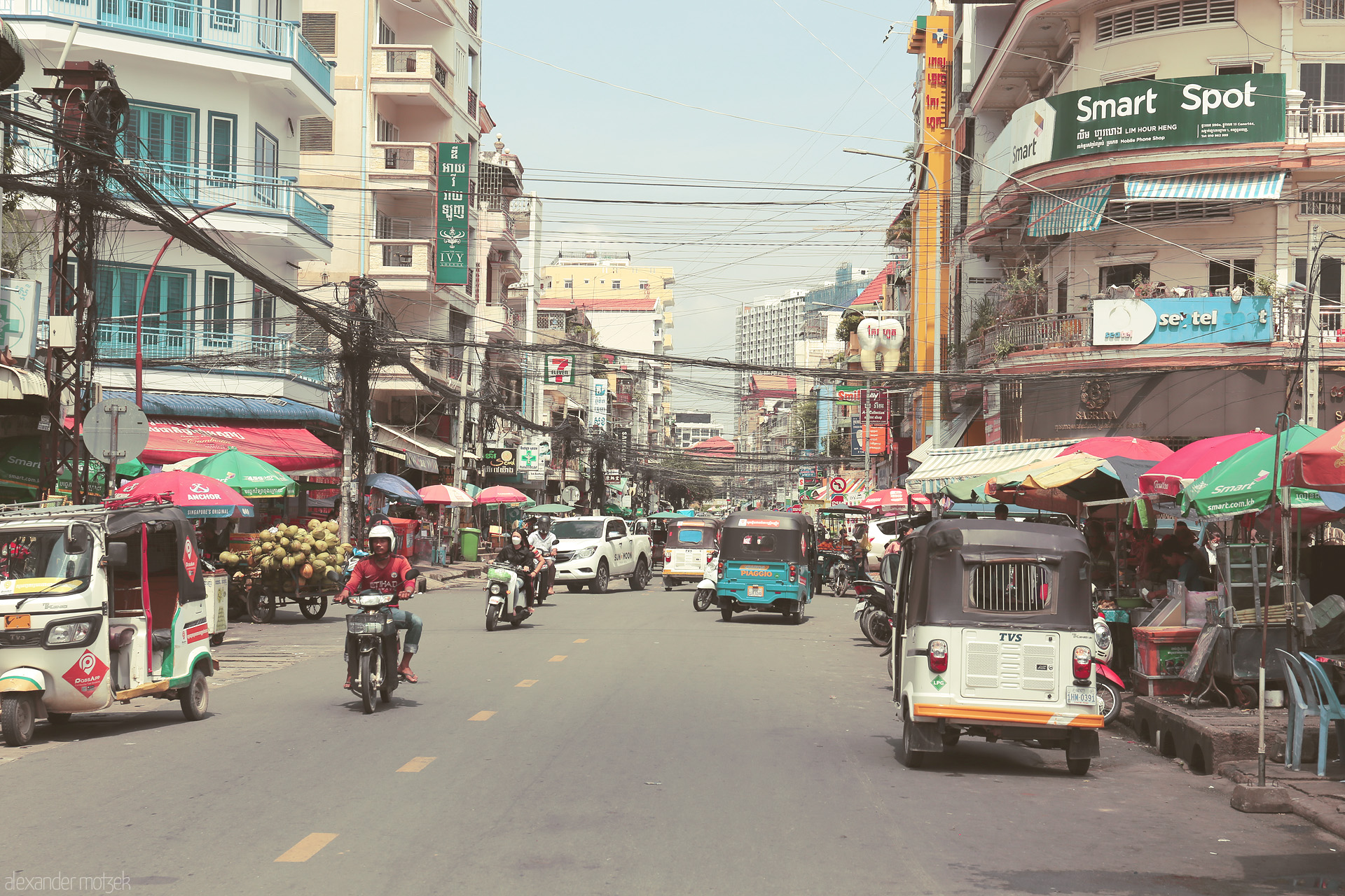 Foto von Bustling tuk tuks and vibrant markets color a typical Phnom Penh street, alive under tangled wires and Khmer signs.