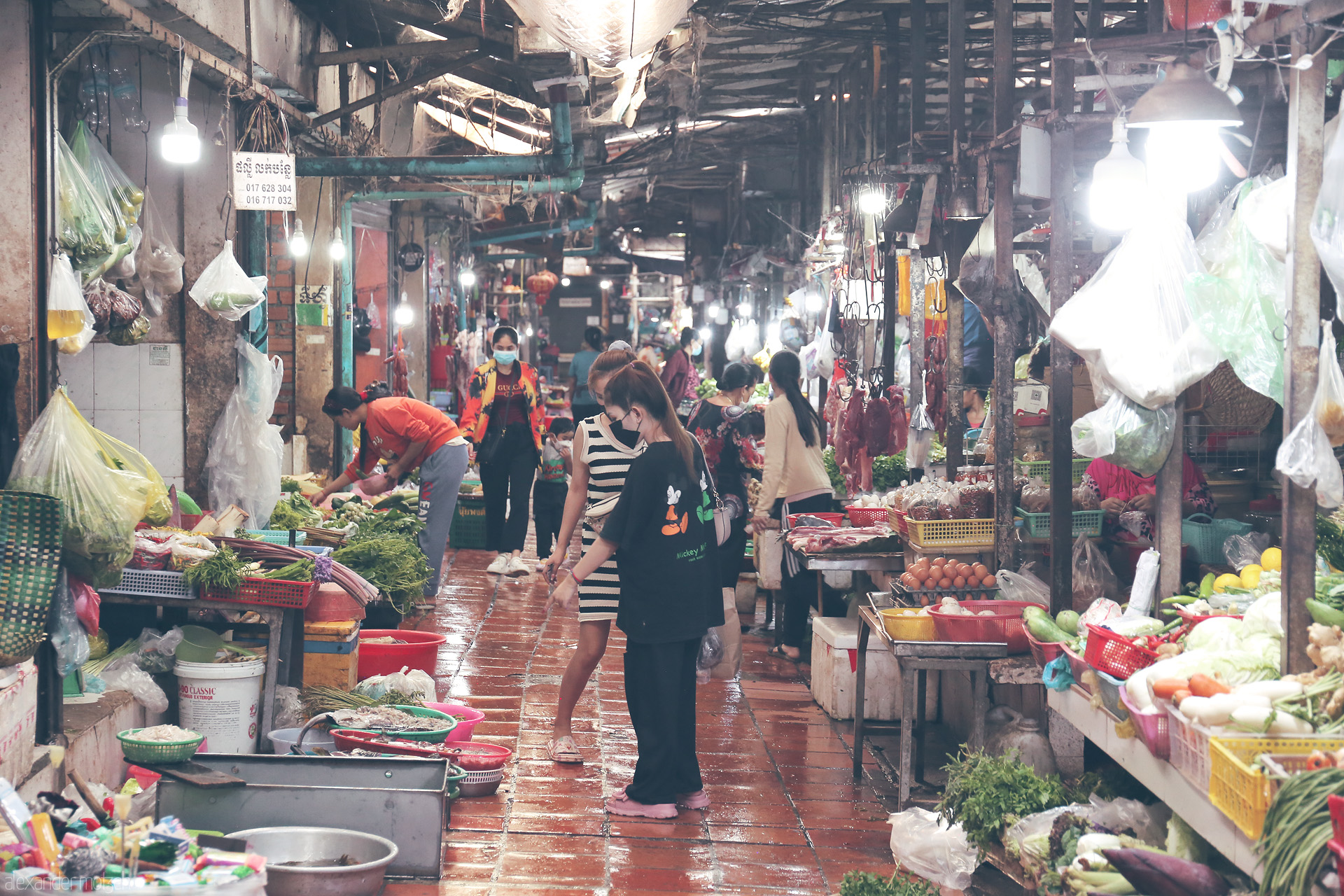 Foto von Bustling vendors and locals line the vibrant, rain-washed aisles of a Phnom Penh market, bursting with fresh produce and Khmer energy.