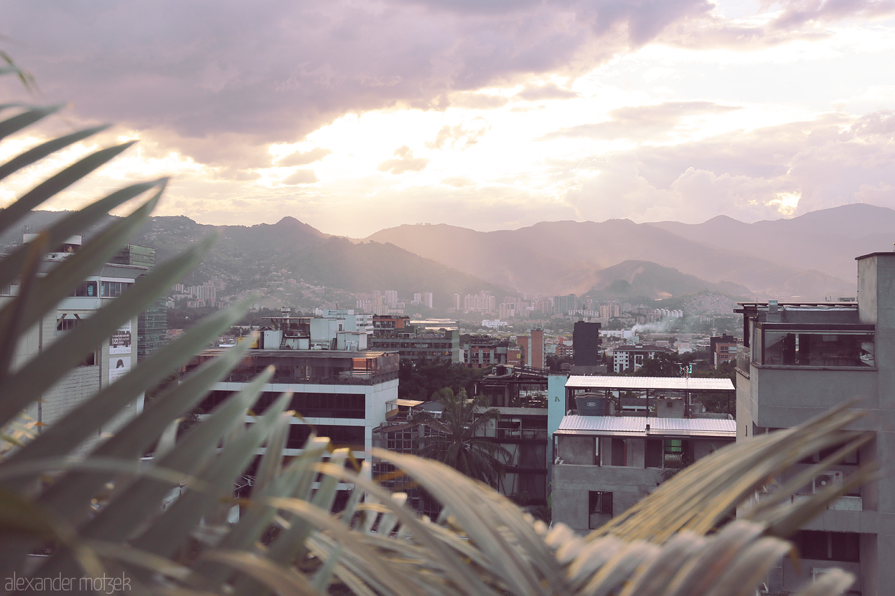 Foto von A breathtaking sunset over Comuna 14 - El Poblado, Medellín, with layered mountains and cityscape, blending nature and urban elements.