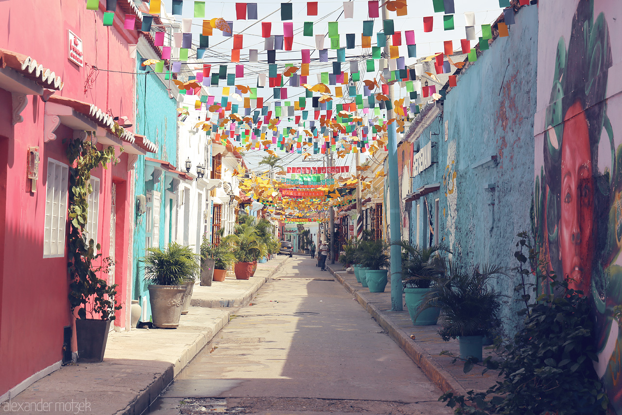 Foto von A lively, colorful street in Cartagena, Colombia, adorned with festive flags, vibrant murals, and flourishing potted plants.