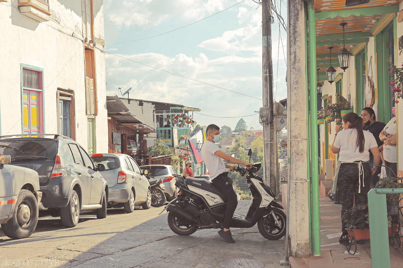 Foto von A lively street in Salento, Quindío, Colombia with vibrant facades, locals, and parked scooters capturing the essence of a bustling Andean town.