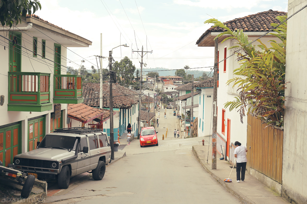 Foto von A serene street in Salento, Colombia with vibrant buildings and a glimpse of local life—where tradition meets nature.