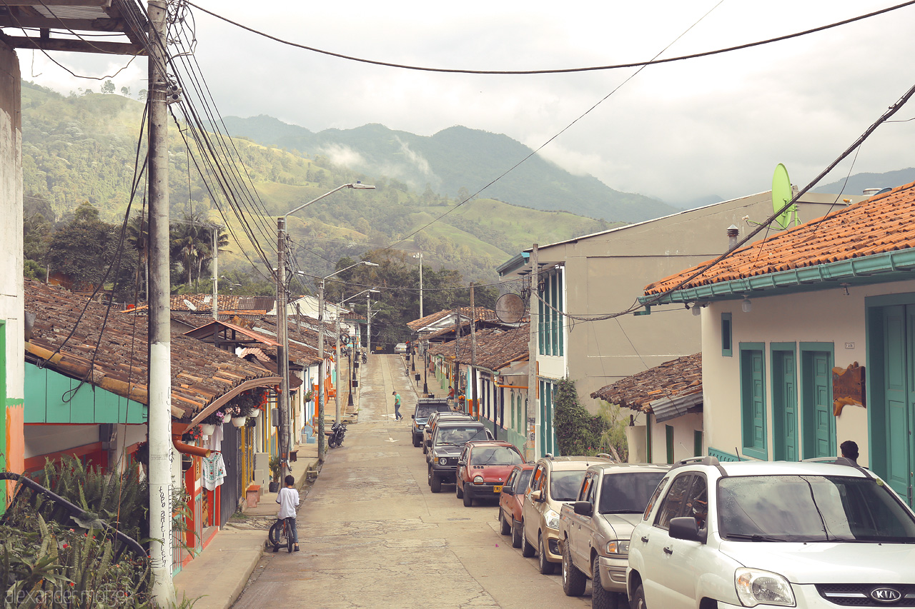 Foto von A tranquil street in Salento, Quindío, where colorful houses and lush mountains create a dreamy view.