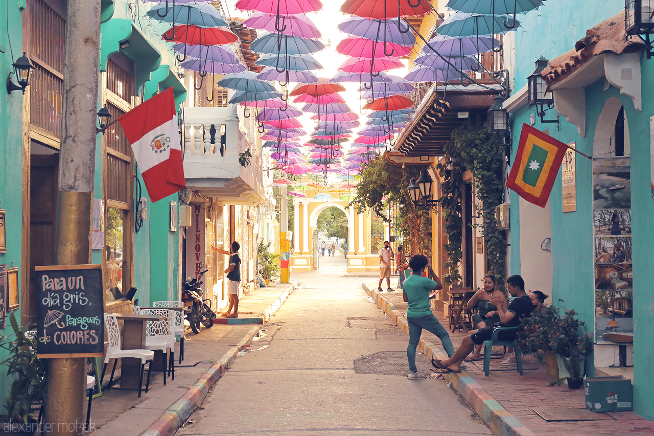 Foto von A vibrant street in Cartagena, Colombia, adorned with colorful umbrellas overhead and quaint cafes lining the cobblestone road.