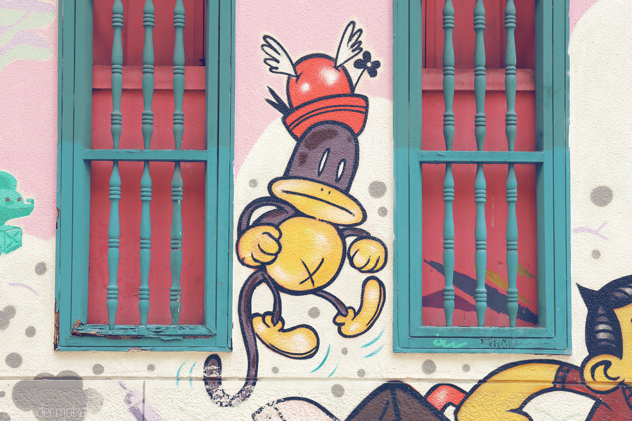 Foto von Bright street art in Comuna 3, Cali, featuring cartoon characters dancing beneath vibrant windows.