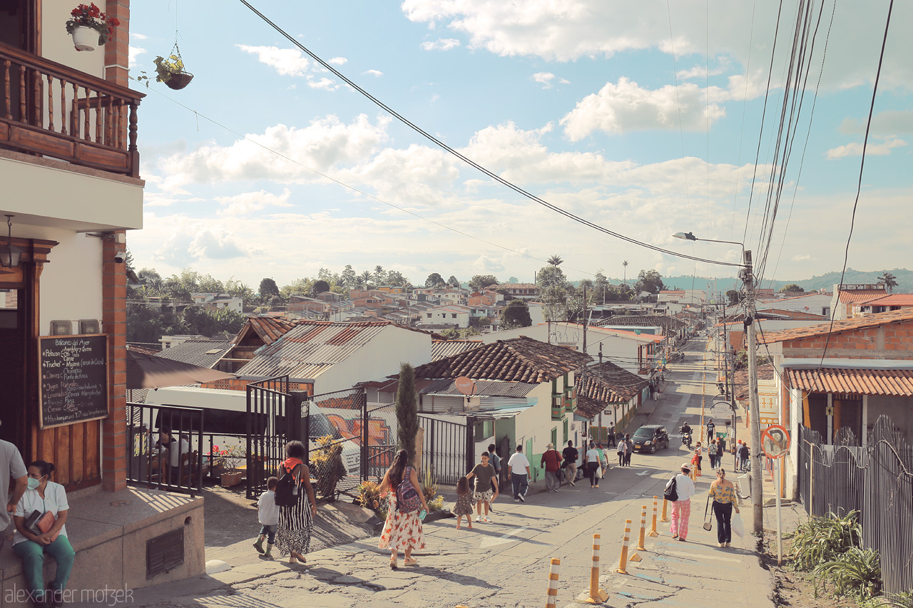 Foto von Bustling day in Salento, Quindío, Colombia, with locals and visitors navigating vibrant streets lined with traditional architecture.