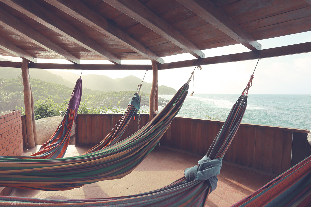 Foto von Colorful hammocks sway gently under a wooden roof, overlooking the pristine coastline of Tayrona, Santa Marta, Colombia.