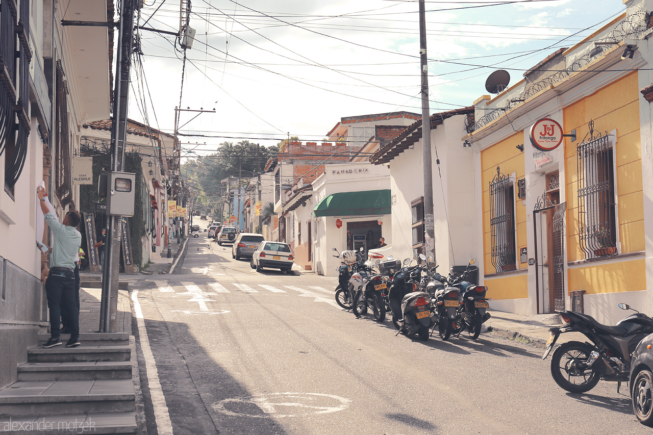 Foto von Discover the quaint streets of Comuna 3, Cali. Traditional architecture embraces a vibrant daily life, marked by motorbikes and local shops.