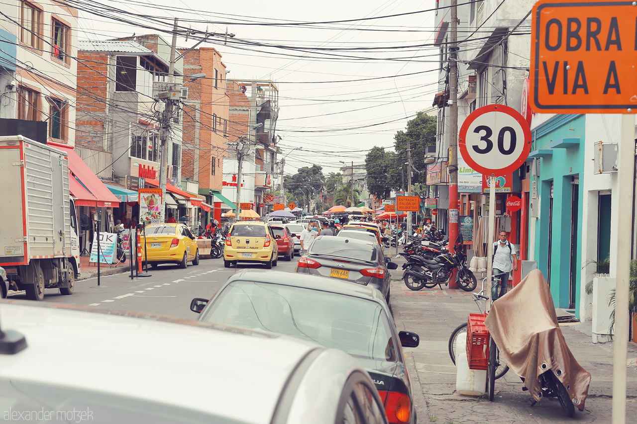 Foto von Lively street scene in Comuna 9, Cali, Colombia with bustling traffic, vibrant shops, and everyday hustle reflecting the city's energetic pulse.