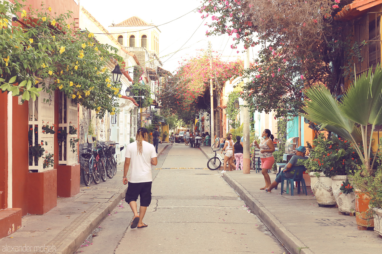 Foto von Warm sun casts over vibrant streets of Cartagena, Colombia, bustling with locals amidst blooming flowers and colorful facades.