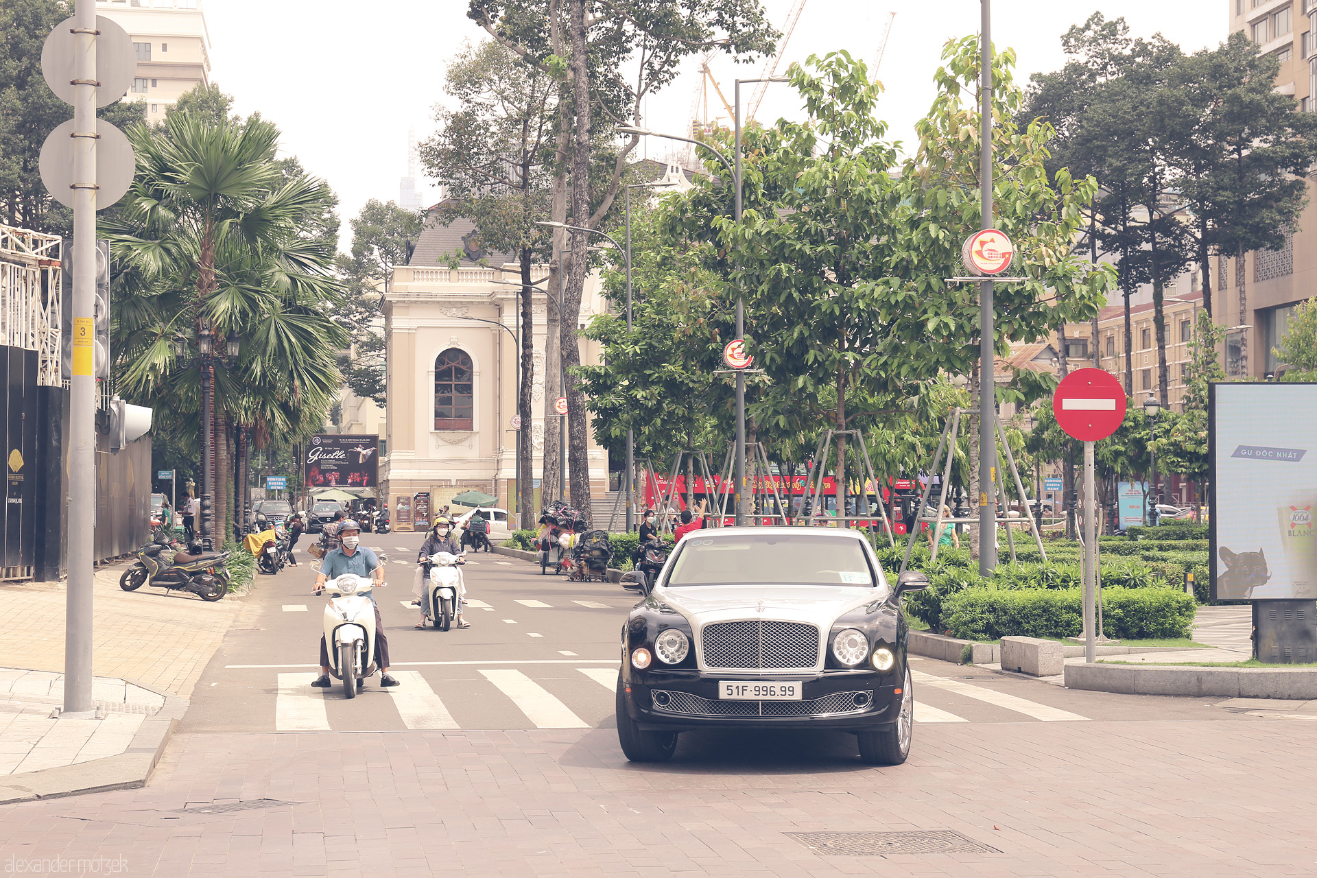 Foto von Contrasts of Ho Chi Minh City: a Bentley glides past scooters and colonial echoes in lush, sunlit Saigon.