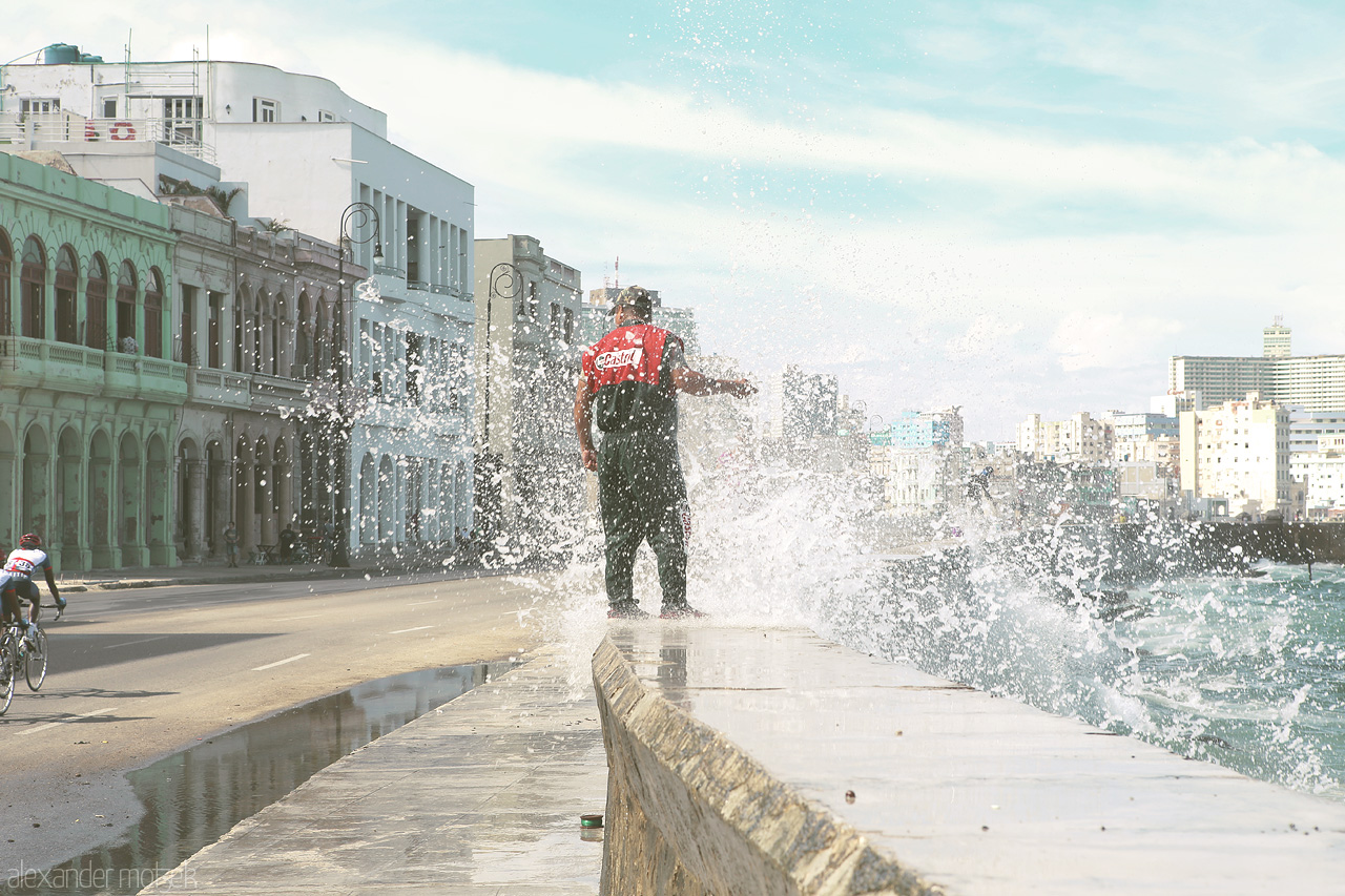 Foto von Ein Fischer wird auf der Ufermauer entlang des Malecón von einer Welle erwischt