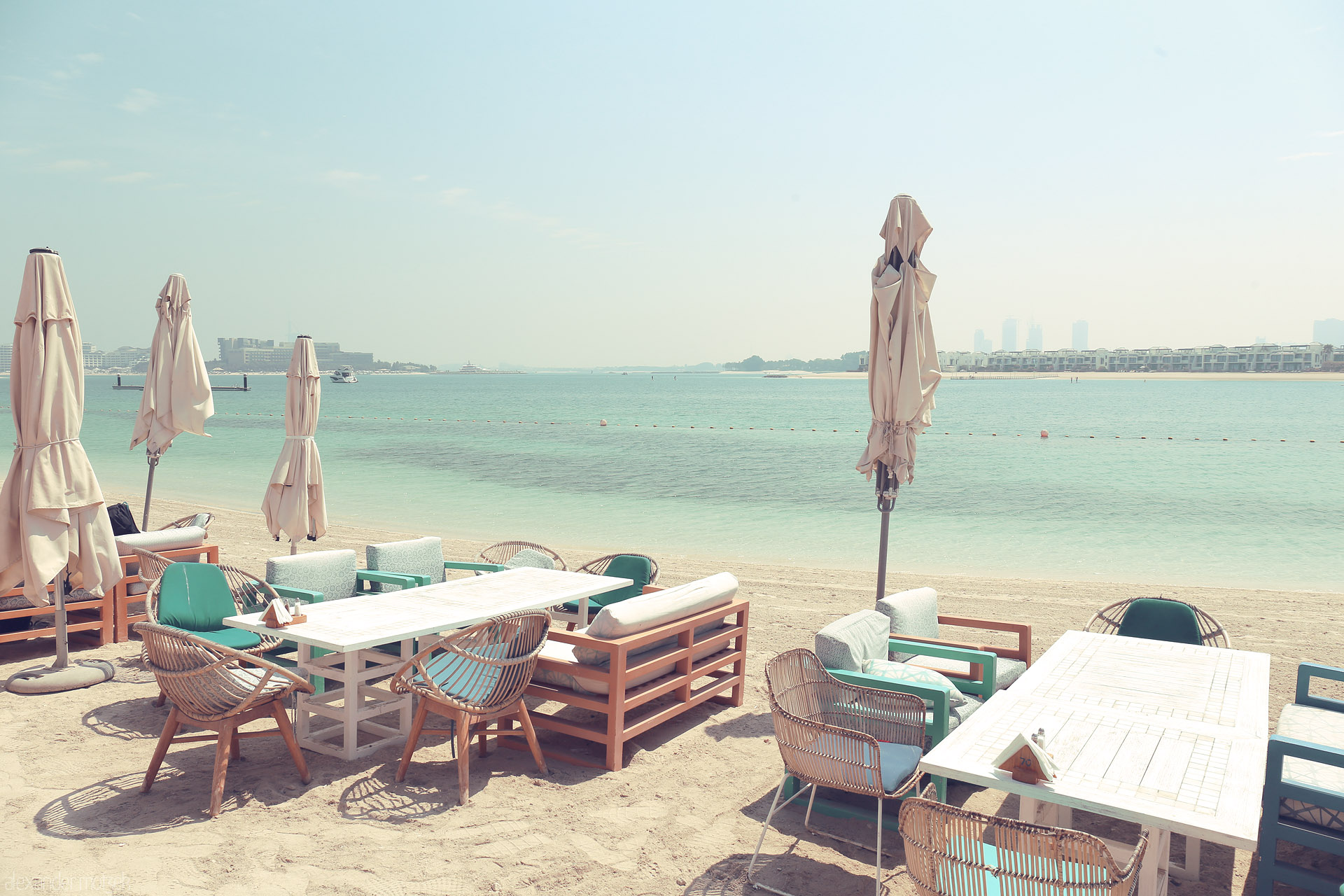 Foto von Chic beachside seating awaits on Dubai’s Palm Jumeirah, where turquoise waters meet sun-soaked serenity.