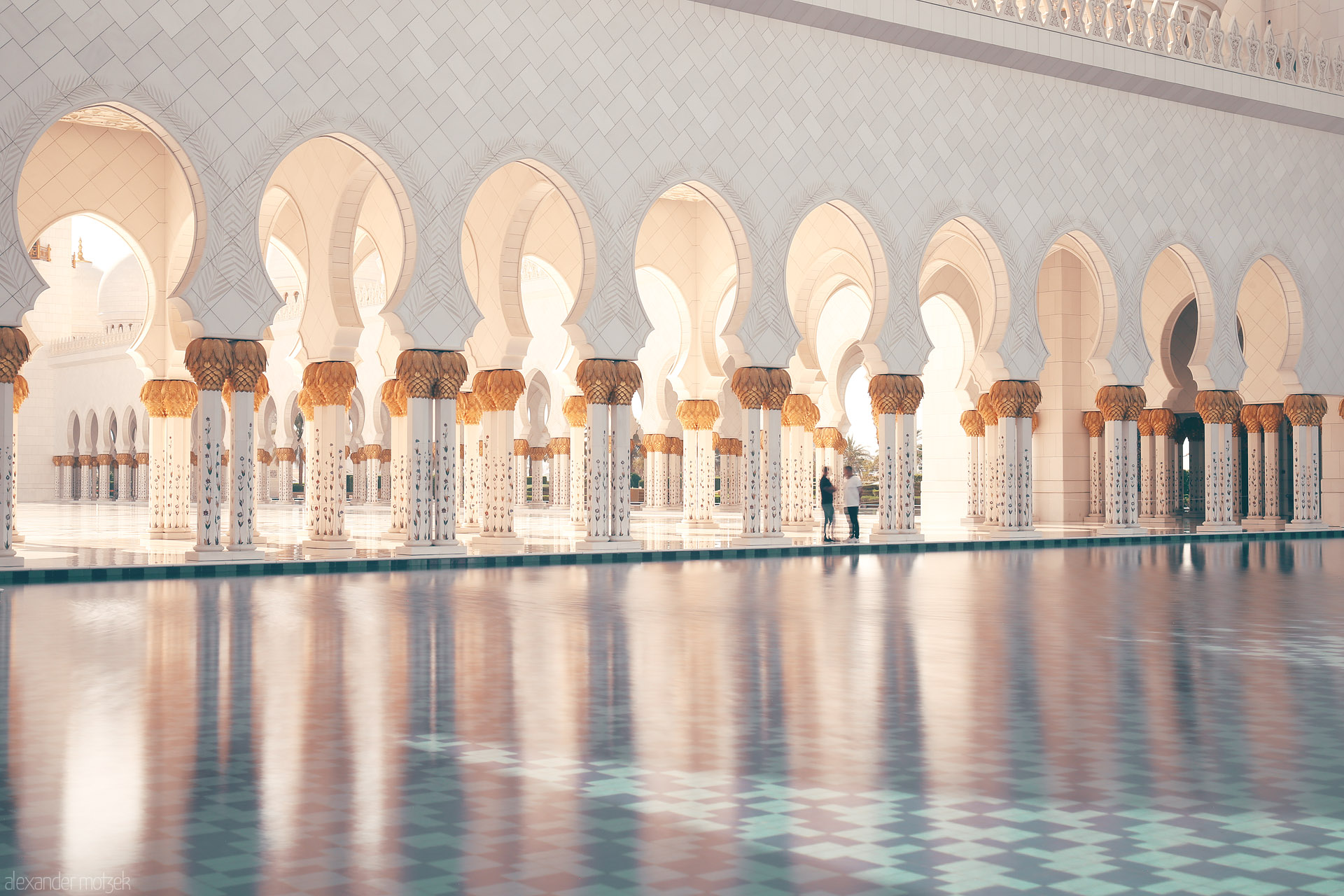 Foto von Golden columns and arched walkways shimmer on tranquil waters at Sheikh Zayed Grand Mosque in Al Rawdah, Abu Dhabi, UAE.