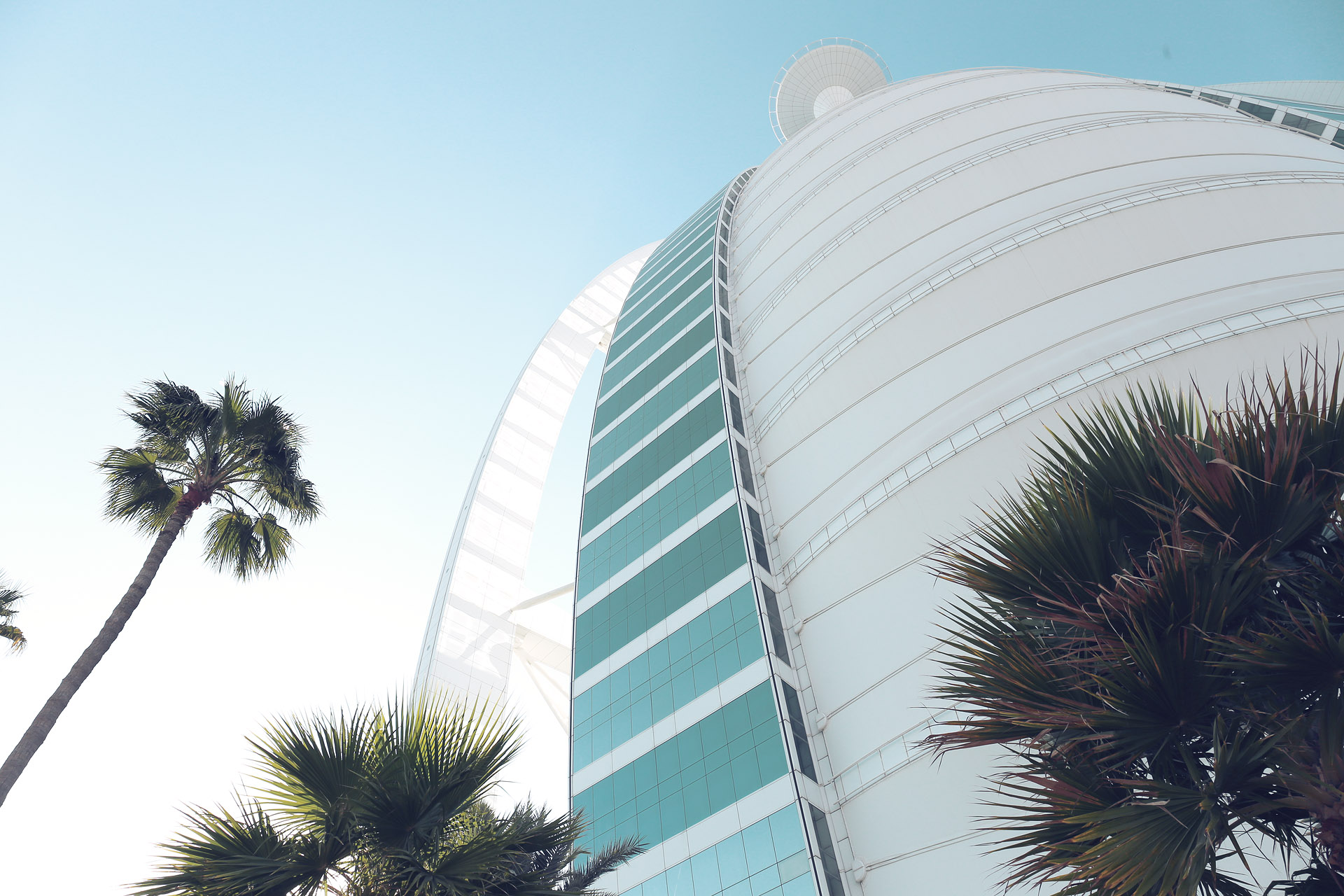 Foto von Palm trees sway beneath the iconic sail-shaped Burj Al Arab, basking in the Dubai sun—a fusion of luxury and desert ambition.