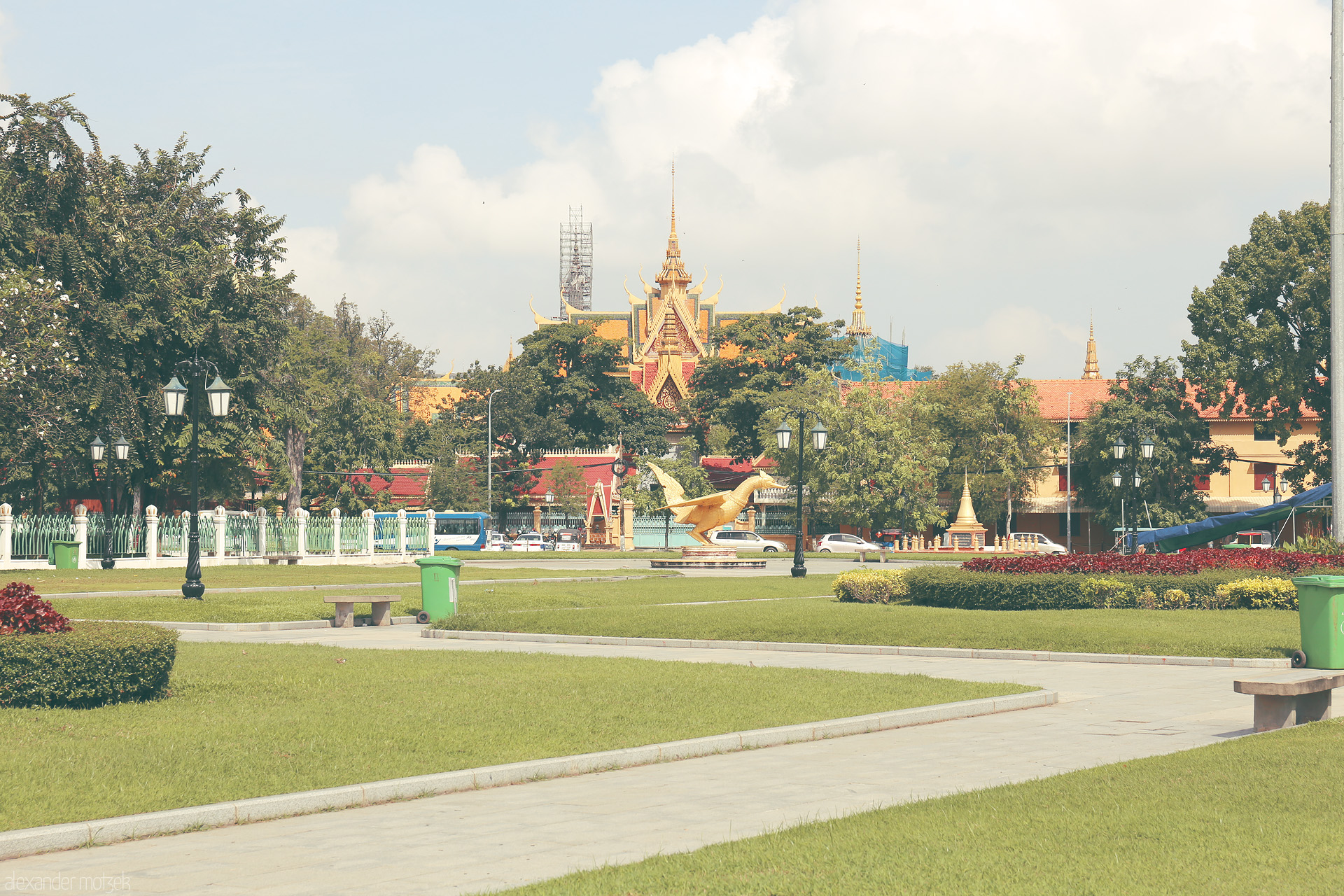 Foto von Golden hsieng bird statue and lush gardens frame ornate Wat Botum in Phnom Penh, Cambodia, beneath tropical skies.