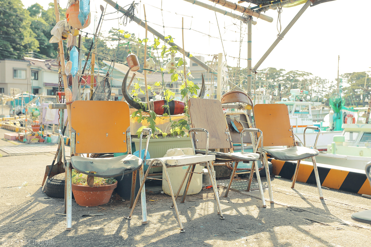 Foto von In Izu, Japan, weathered chairs sit by the harbor, quietly whispering tales of the shimmering sea and serene morning light.