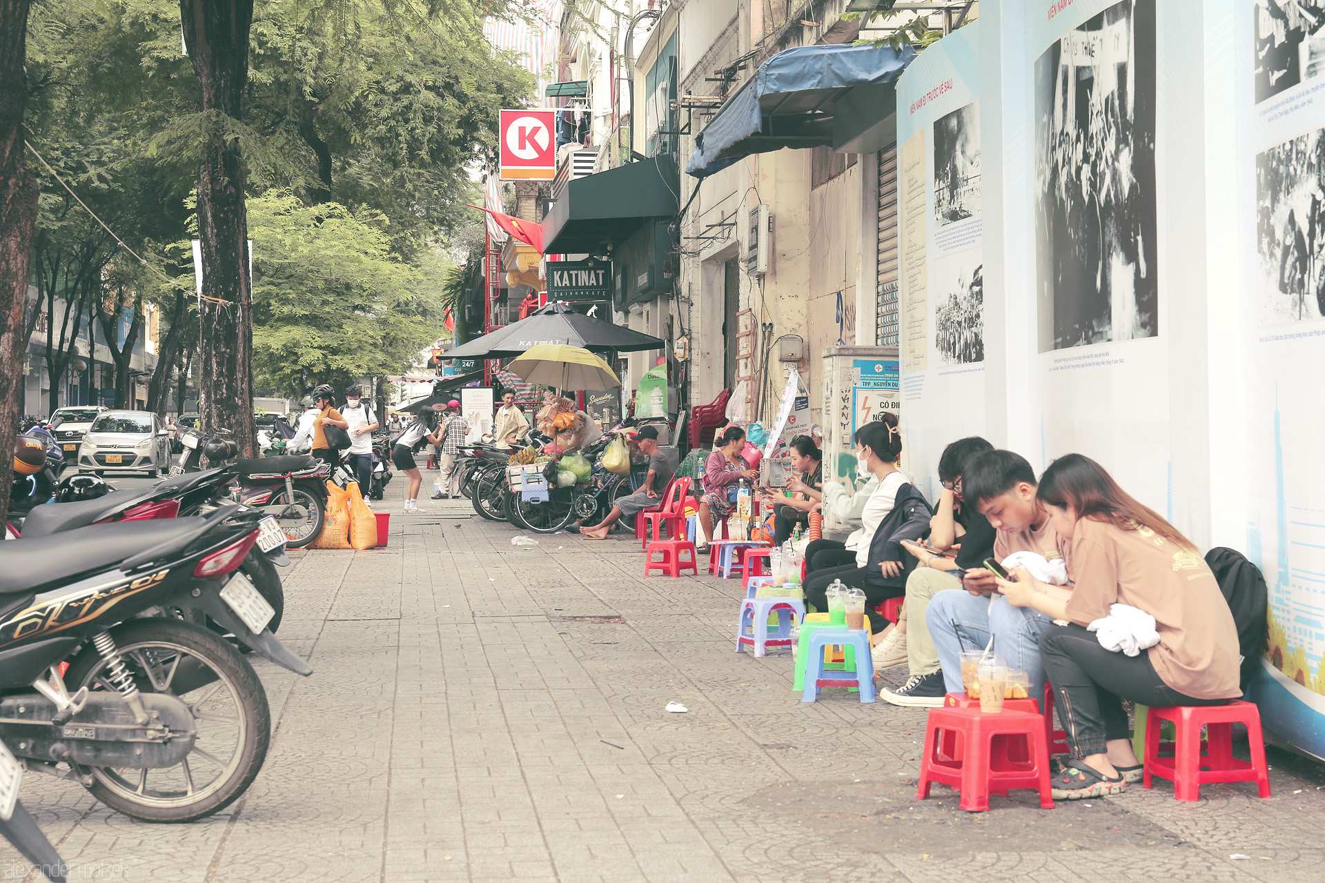 Foto von Locals gather on tiny stools, sipping iced coffee beneath urban trees in vibrant Saigon, Vietnam—where street life tells a thousand tales.