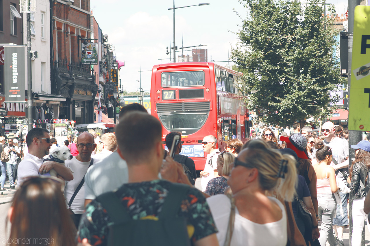 Foto von Bustling London street alive with crowds and iconic red bus on a sunny day.