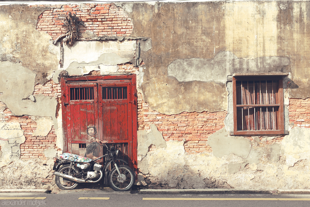 Foto von A child astride a motorbike, painted by Ernest Zacharevic, graces a weathered wall in Penang, capturing the heart of Malaysia's street art scene.