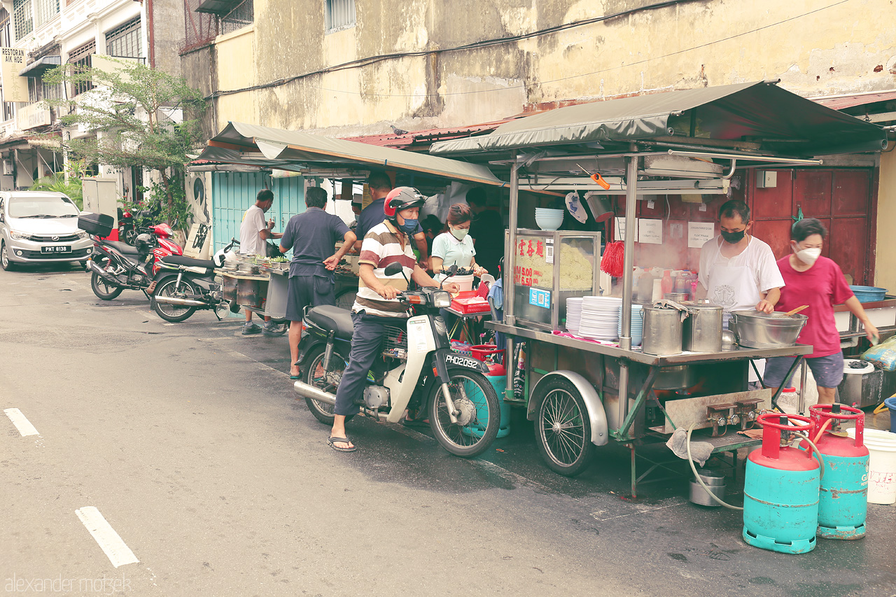 Foto von Bustling street food scene in Penang, Malaysia, with locals savoring culinary delights from vibrant stalls.