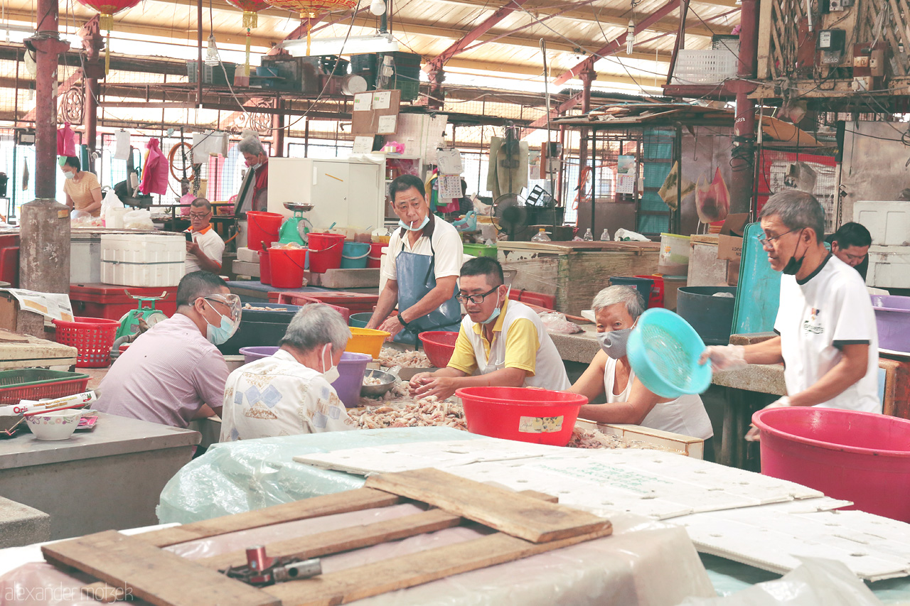 Foto von Locals in Penang gather at a vibrant market, showcasing teamwork and tradition in a bustling atmosphere.