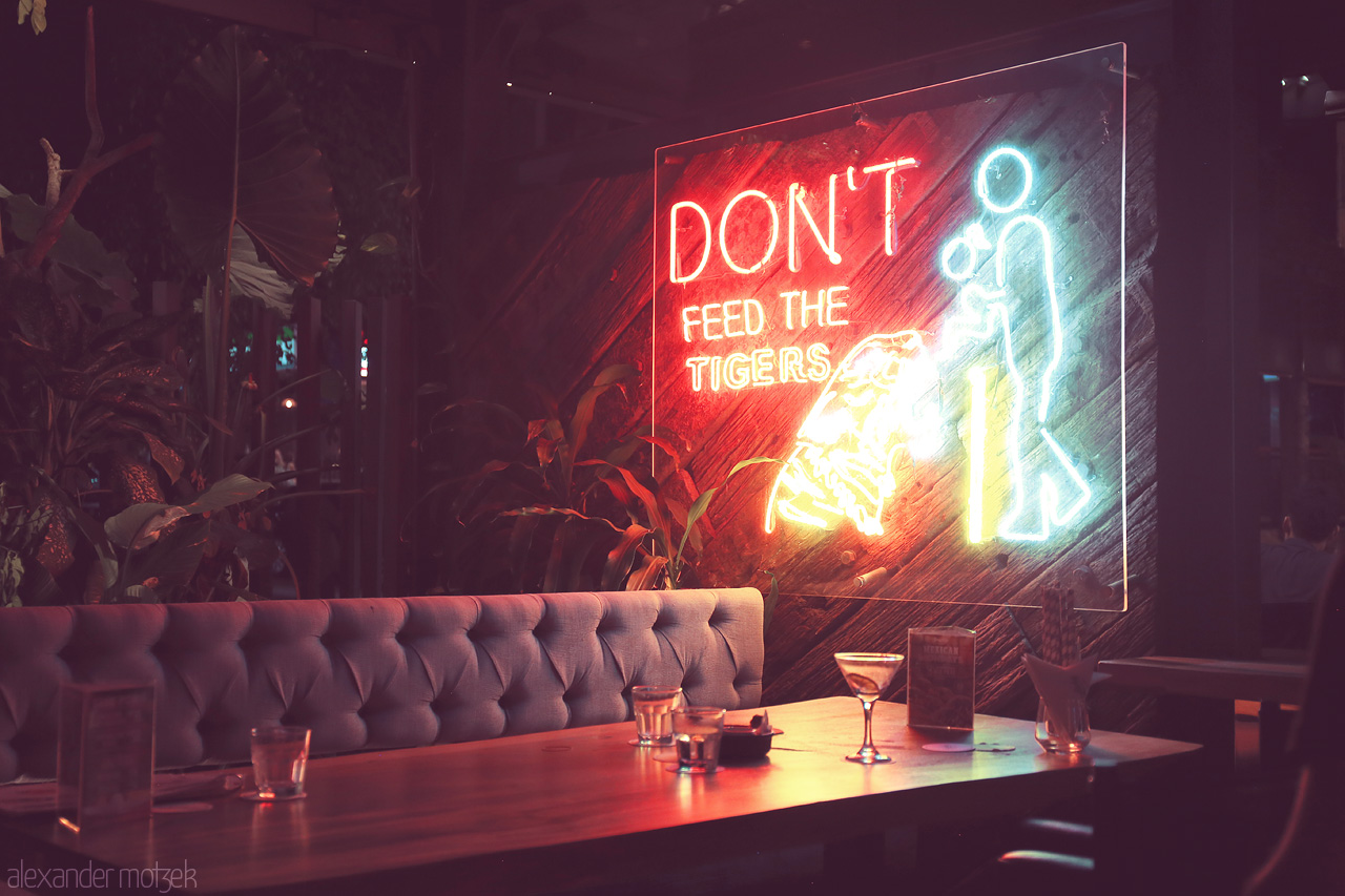 Foto von Neon lights in a Kuala Lumpur café create an urban jungle vibe with a playful 'Don't Feed the Tigers' sign.