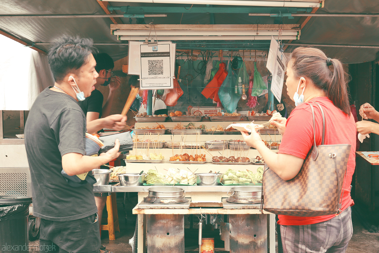 Foto von Vibrant street food stall in Penang, Malaysia, with locals indulging in diverse flavors. A culinary journey through the heart of Lorong's bustling lanes.