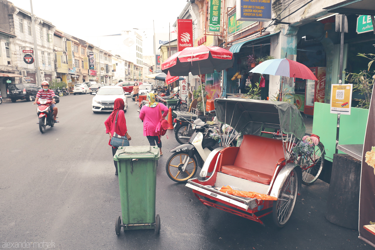 Foto von Vibrant street life in Penang with traditional trishaws, lively colors, and bustling roadside views.