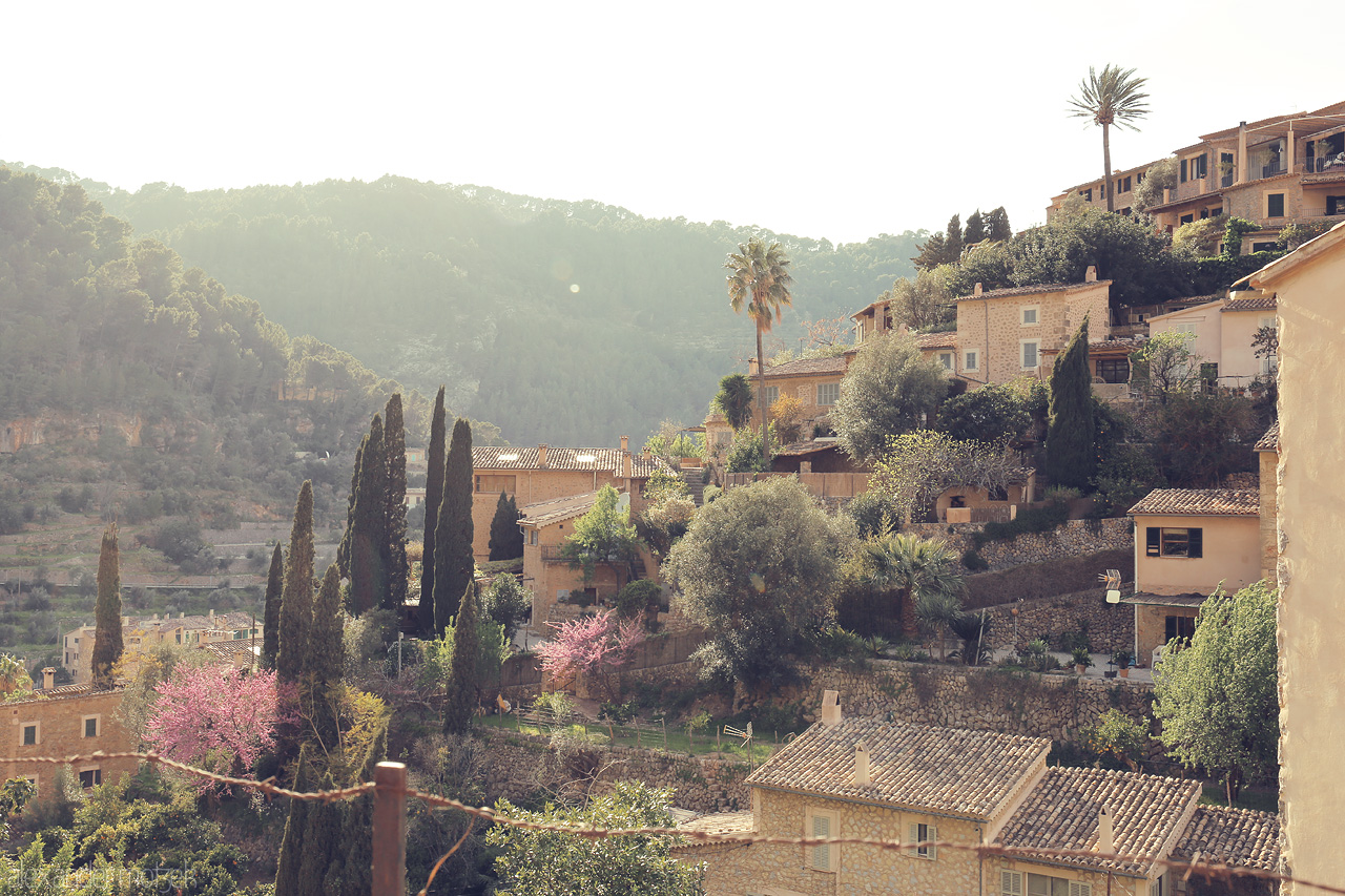 Foto von Warm sunlight bathes the terracotta rooftops and lush greenery of Deià, a rustic gem tucked in the Tramuntana mountains.