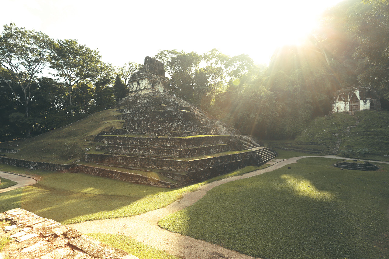 Foto von Ancient Mayan ruins at Palenque bathed in the golden glow of the setting sun.