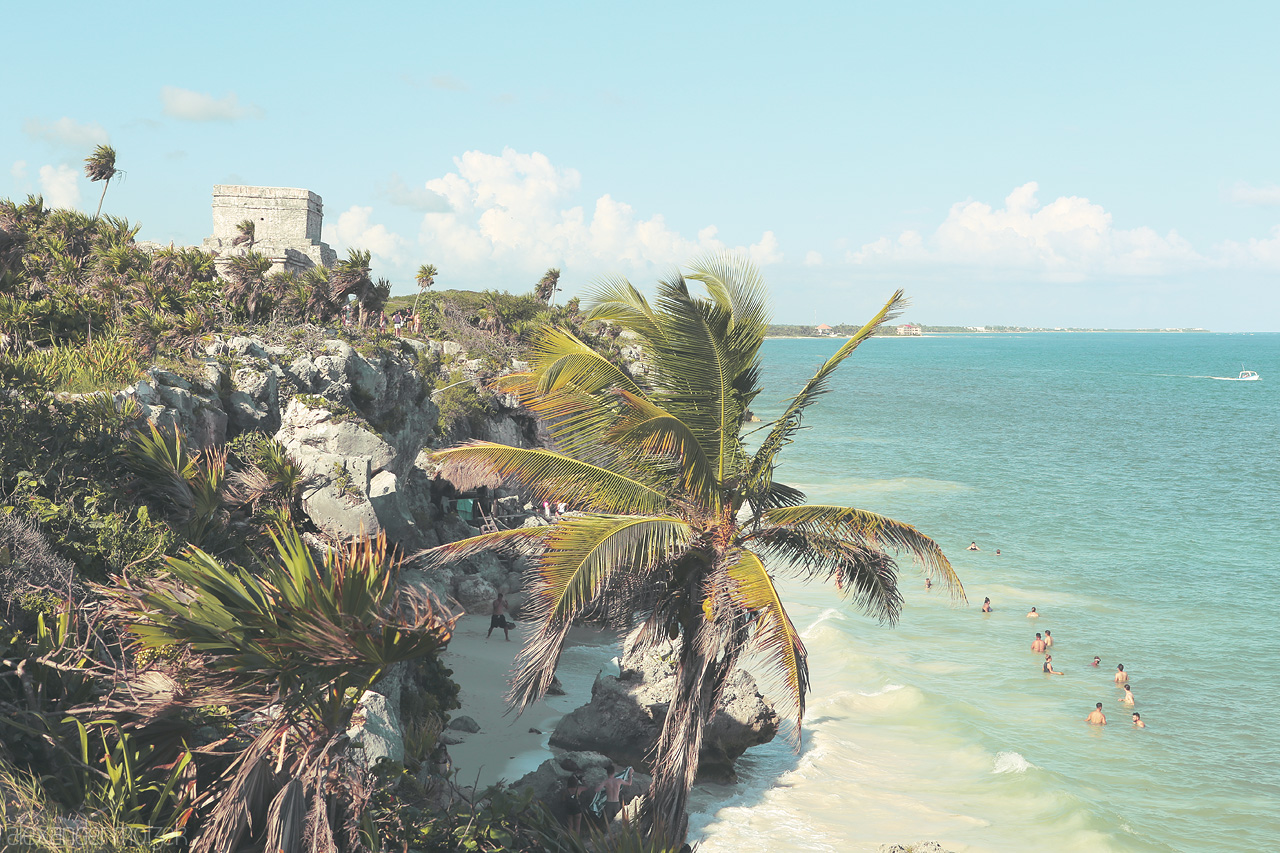 Foto von Ancient ruins overlook a tropical beach with swaying palms and turquoise waters in Tulum, Mexico.