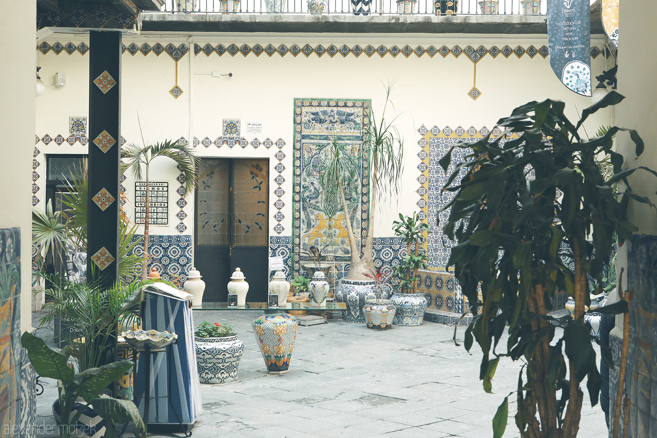 Foto von Ceramic-tiled courtyard with traditional Talavera pottery amidst lush greenery in Puebla, Mexico.