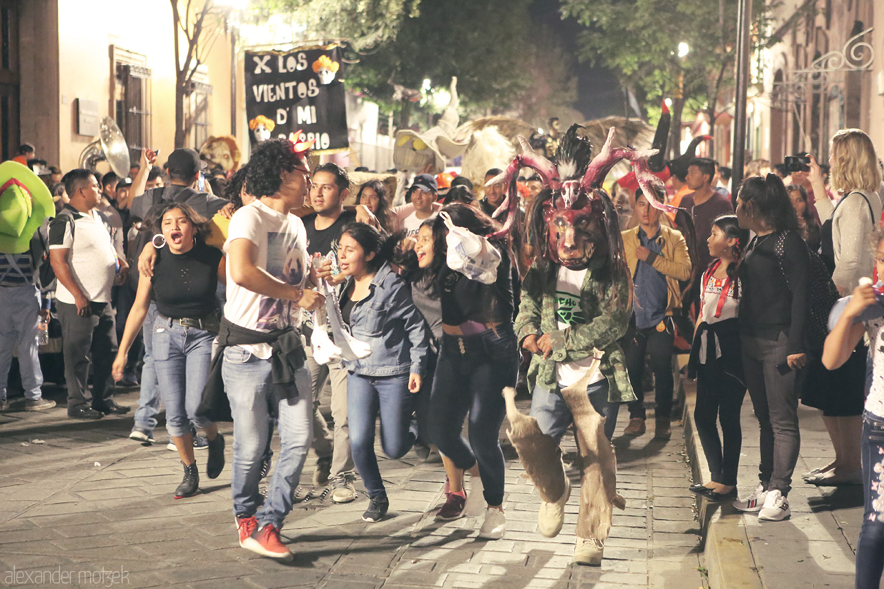 Foto von Energetic street celebration at night in Oaxaca de Juárez, with vibrant local costumes and joyful crowd for the dia de los muertos.