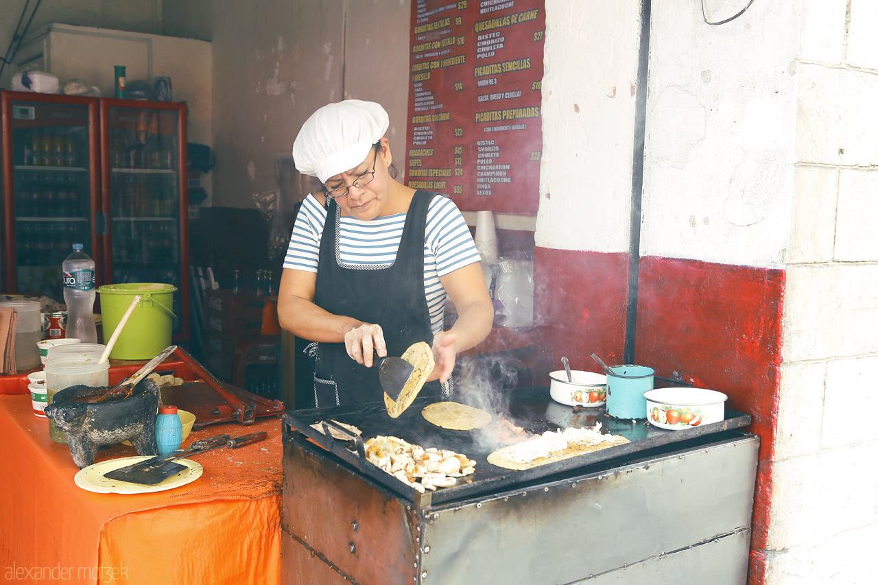 Foto von Local chef in Puebla, Mexico preparing traditional tacos on a bustling street corner.